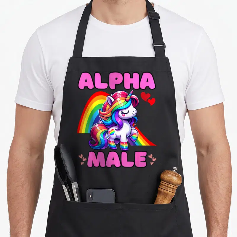 Tablier de cuisine noir avec une licorne arc-en-ciel posant devant un arc-en-ciel et le texte Alpha Male en lettres roses.