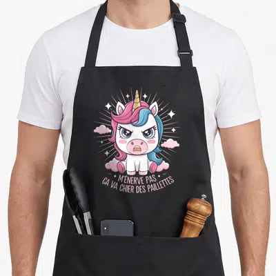 Tablier de cuisine noir avec illustration d'une licorne fâchée aux cheveux roses et bleus, entourée de nuages et d'étoiles.