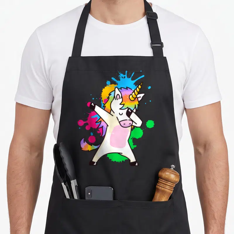 Tablier de cuisine noir avec illustration d'une licone blanche effectuant la pose dab entourée d'éclaboussures de couleurs vives.