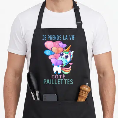 Tablier de cuisine noir avec une licorne multicolore tenant des cœurs et le texte Je Prends La Vie Côté Paillettes.