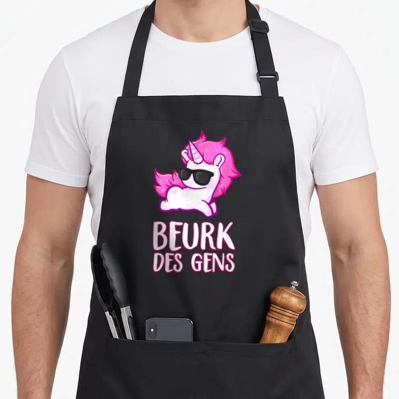 Tablier de cuisine noir avec une licorne rose portant des lunettes noires et le texte Beurk des gens imprimé en blanc.
