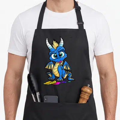 Tablier de cuisine noir avec illustration d'un dragon bleu mangeant des crayons de couleur multicolores sur le devant.