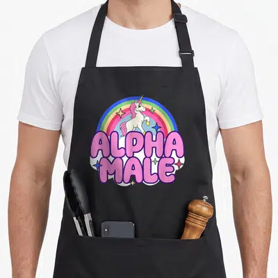 Tablier de cuisine noir avec illustration d'une licorne sous arc-en-ciel et le texte Alpha Male en lettres roses.