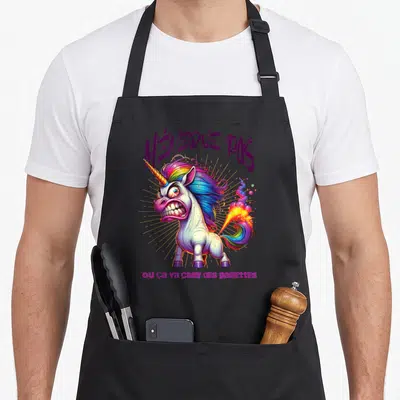 Tablier de cuisine noir avec licorne furieuse aux cheveux arc-en-ciel et texte humoristique imprimé en violet et rose.