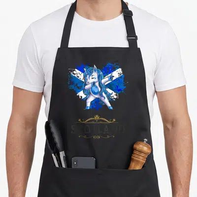 Tablier de cuisine noir avec une licorne bleue faisant le dab sur un drapeau écossais et le mot SCOTLAND.