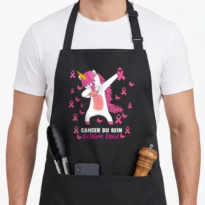 Tablier de cuisine noir avec licone blanche en pose dab entourée de rubans roses et papillons sur fond uni.