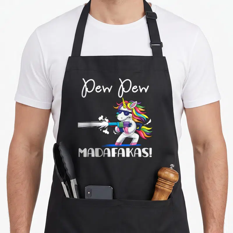 Tablier de cuisine noir avec licorne portant des lunettes noires et tenant une arme émettant un rayon blanc, texte Pew Pew Madafakas en blanc.