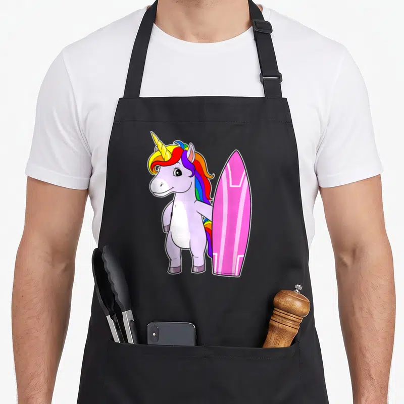 Tablier de cuisine noir avec illustration d'une licorne surfeuse rose et une planche de surf arc-en-ciel