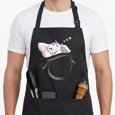 Tablier de cuisine noir avec licorne blanche dormant sur oreiller rose et ZZZ au-dessus.