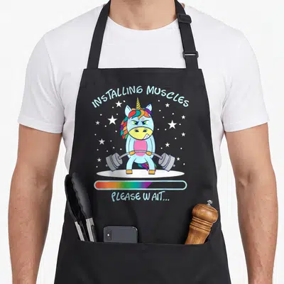 Tablier de cuisine noir avec licorne bleue levant une barre de poids sous un ciel étoilé et une barre de progression rainbow.
