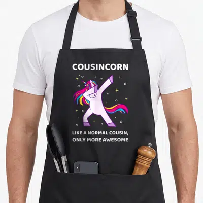Tablier de cuisine noir avec une licorne rose faisant le dab et des étoiles scintillantes autour.