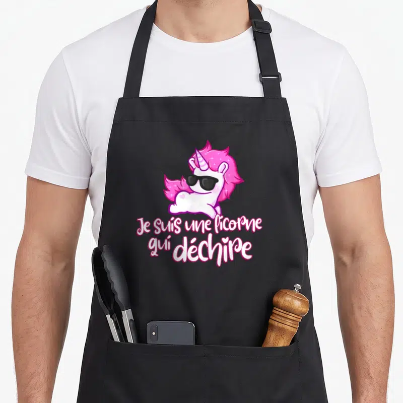 Tablier de cuisine noir avec licorne rose aux lunettes noires et texte Je suis une licorne qui déchire imprimé au centre.