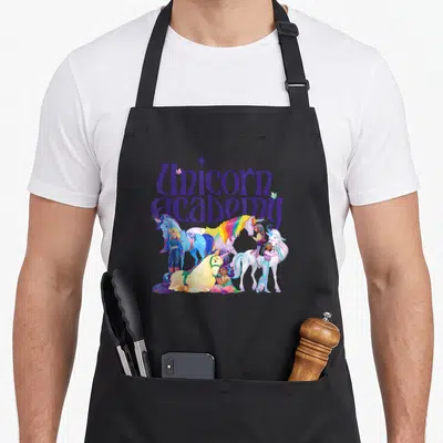 Tablier de cuisine noir avec illustration colorée de cavaliers et de licornes sous le titre Unicorn Academy en lettres violettes.