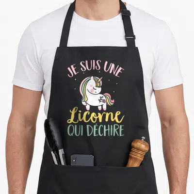 Tablier de cuisine noir avec une licorne rose et le texte Je suis une Licorne qui déchire imprimé en couleurs pastel.