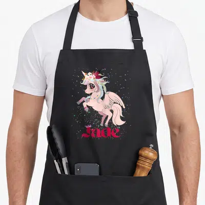 Tablier de cuisine noir avec une licorne ailée rose portant une couronne de fleurs et le prénom Jade en lettres roses.