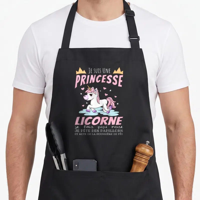 Tablier de cuisine noir avec une illustration de licorne rose et les mots Je Suis Une Princesse Licorne imprimés en haut et en bas.