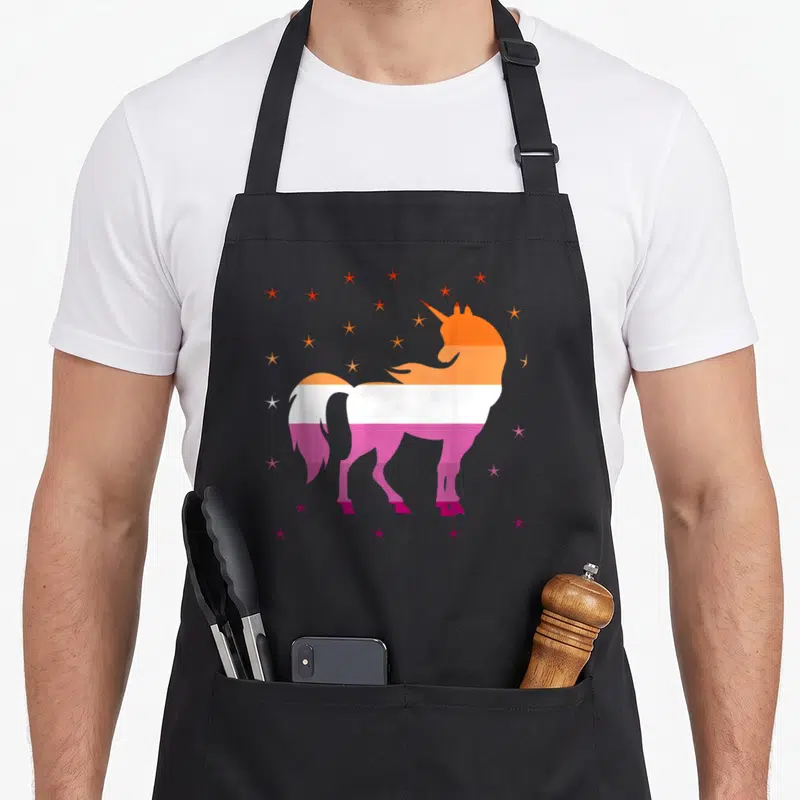 Tablier de cuisine noir avec une licorne aux couleurs du drapeau lesbien et des étoiles multicolores.