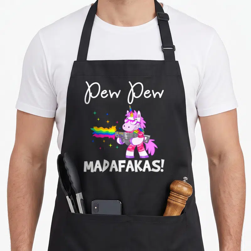 Tablier de cuisine noir avec licorne rose tirant un arc-en-ciel et texte blanc.
