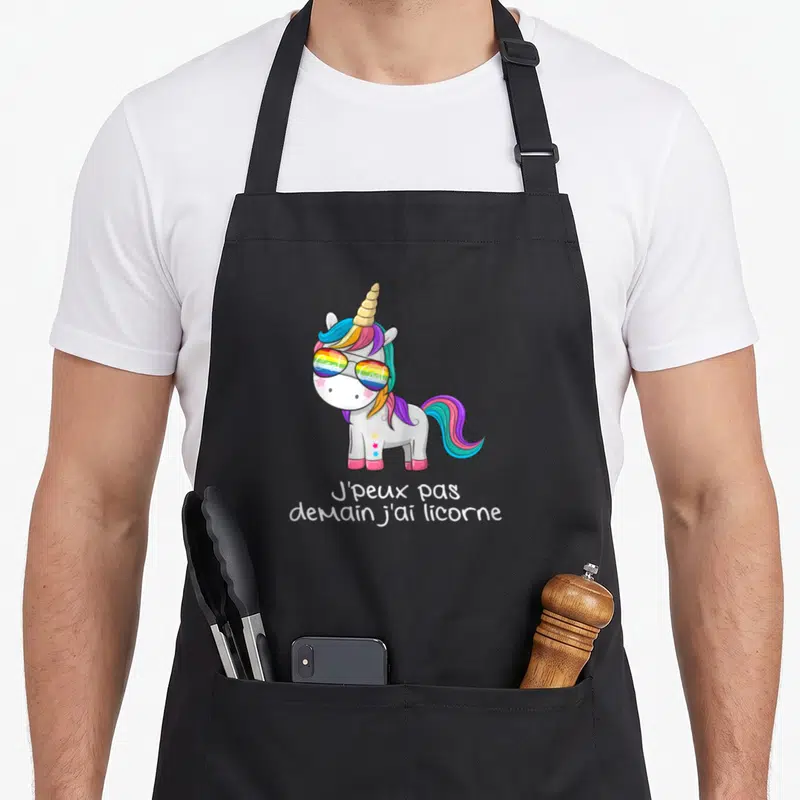 Tablier de cuisine noir avec une licorne aux lunettes de soleil et un texte humoristique en blanc.