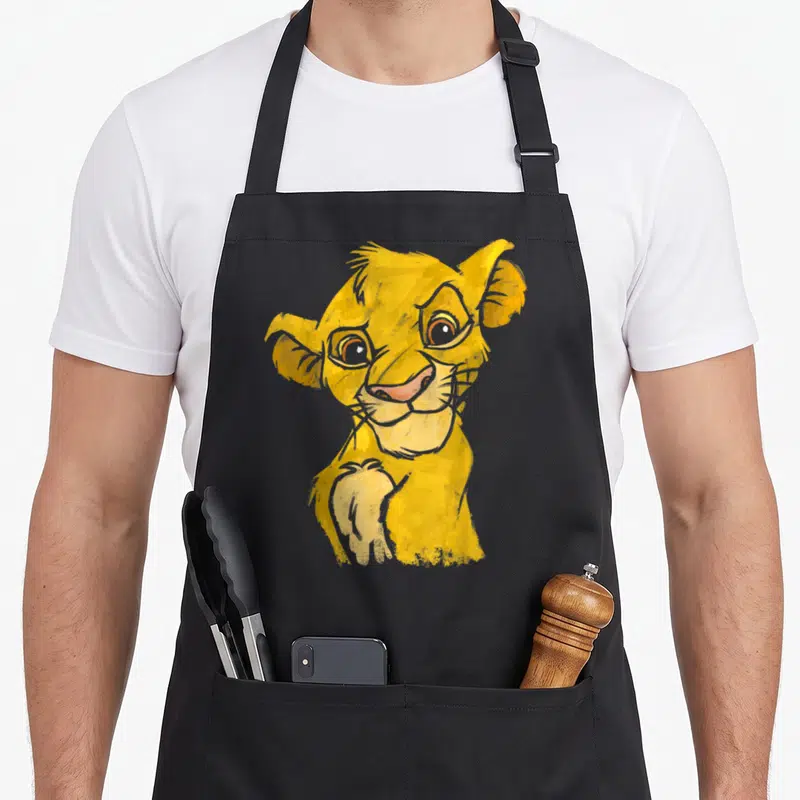 Tablier de cuisine noir avec portrait sketch coloré d'un jeune lion jaune souriant levant une patte