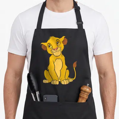 Tablier de cuisine noir avec un lionceau jaune assis au regard doux et à la queue touffue.