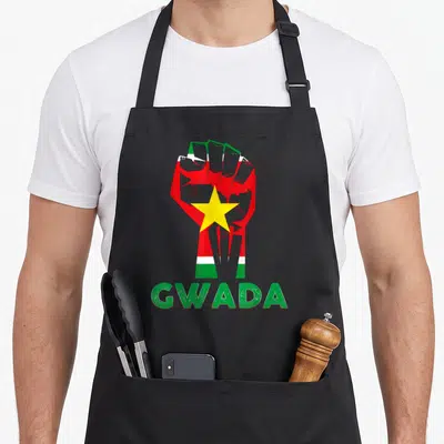 Tablier de cuisine noir avec un poing levé aux couleurs du drapeau Guadeloupe et le mot GWADA en vert.