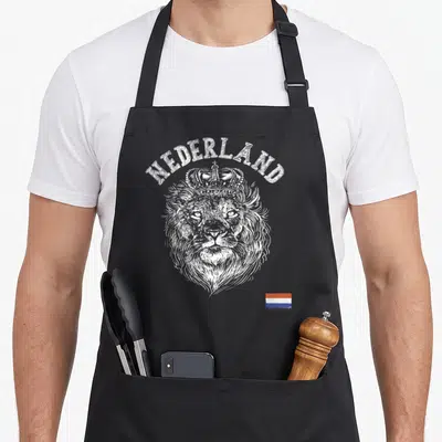 Tablier de cuisine noir avec tête de lion couronné, inscription Nederland et petit drapeau tricolore en bas à droite.