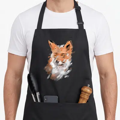 Tablier de cuisine noir avec illustration stylisée d'un renard aux yeux orange et au pelage roux et blanc.