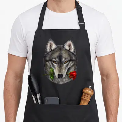 Tablier de cuisine noir avec tête de loup gris tenant une rose rouge dans sa bouche.