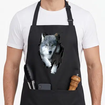 Tablier de cuisine noir avec illustration d'un loup blanc marchant vers l'avant les yeux fixateurs et une patte tendue.