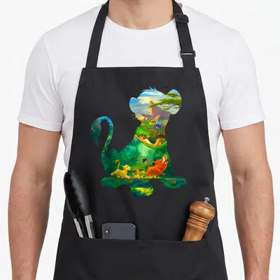 Tablier de cuisine noir avec silhouette de lion remplie de scènes africaines et de personnages animés colorés.