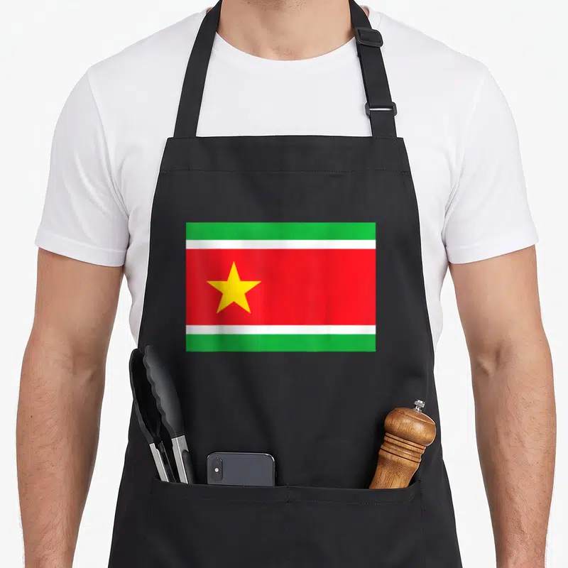 Tablier de cuisine noir avec un emblème de la Guadeloupe comportant une étoile jaune sur fond rouge encadré de bandes vertes et blanches.