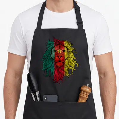 Tablier de cuisine noir avec un lion aux cheveux verts rouges et jaunes style drapeau camerounais