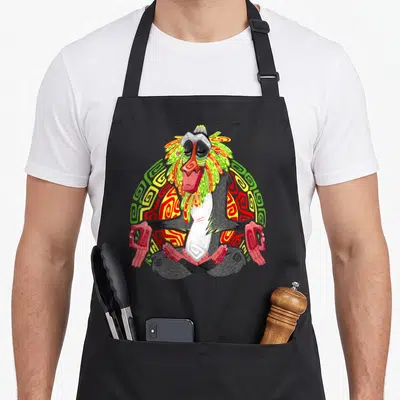 Tablier de cuisine noir avec Rafiki assis en tailleur et les yeux fermés au milieu de motifs tribaux colorés.