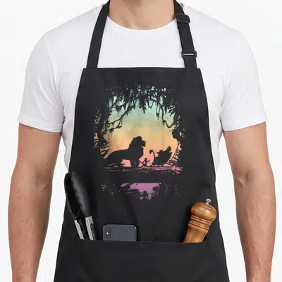 Tablier de cuisine noir avec silhouette de lion et amis dans une arche végétale aux couleurs douces.
