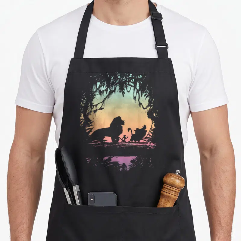 Tablier de cuisine noir avec silhouette de lion et amis dans une arche végétale aux couleurs douces.