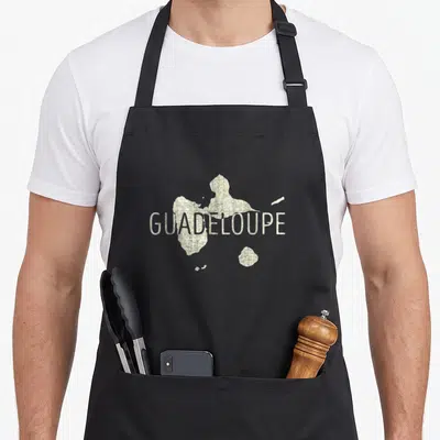 Tablier de cuisine noir avec carte de la Guadeloupe et le texte GUADELOUPE en lettres claires au centre.