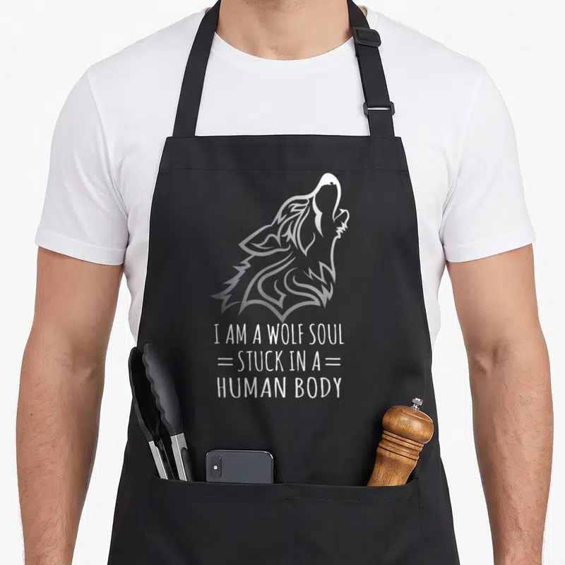 Tablier de cuisine noir avec illustration d'un loup hurlant et texte blanc I AM A WOLF SOUL STUCK IN A HUMAN BODY.
