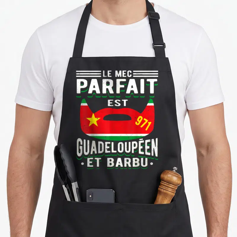 Tablier de cuisine noir avec une barbe rouge verte et jaune portant l'inscription Le mec parfait est Guadeloupéen et barbu 971.