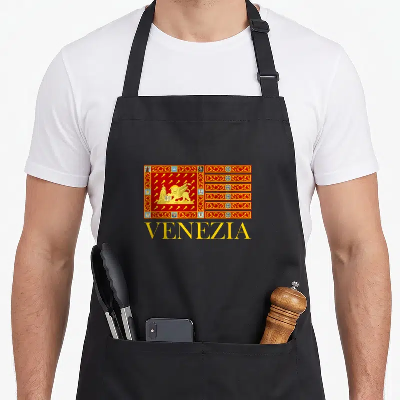 Tablier de cuisine noir avec le drapeau de Venise, le lion doré de Saint Marc et le mot Venezia en jaune.