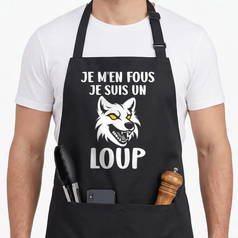 Tablier de cuisine noir avec une tête de loup blanche aux yeux jaunes et le texte Je m'en fous je suis un loup.