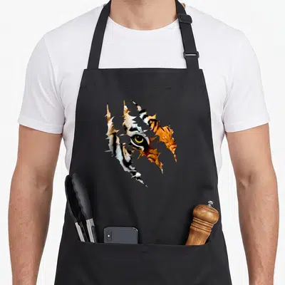 Tablier de cuisine noir avec illustration d'un œil de tigre traversant une surface déchirée