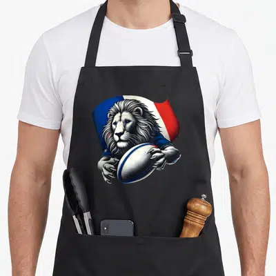 Tablier de cuisine noir avec illustration d'un lion tenant un ballon de rugby sur fond tricolore français.