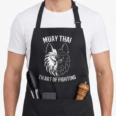 Tablier de cuisine noir avec tête de loup bicolore et texte Muay Thai en blanc sur fond uni.
