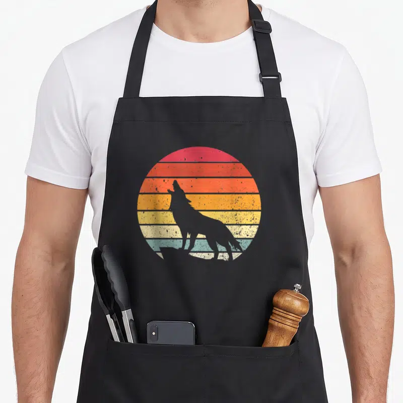 Tablier de cuisine noir avec silhouette loup hurlant devant un soleil couchant rayé retro