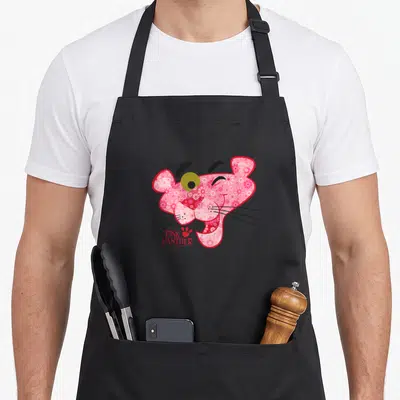 Tablier de cuisine noir avec la grande face de la panthère rose remplie de motifs floraux roses et blancs.