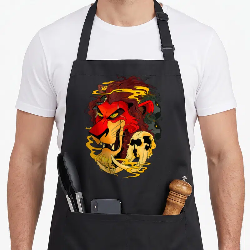 Tablier de cuisine noir avec illustration d'un lion aux yeux verts, mane rouge et crâne blanc stylisé.