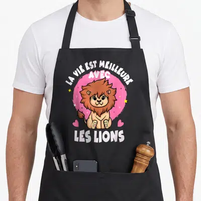 Tablier de cuisine noir avec un lion cartoon souriant et la phrase La vie est meilleure avec les lions.
