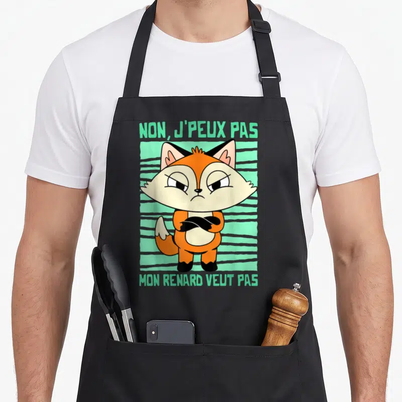 Tablier de cuisine noir avec un renard orange aux bras croisés et le texte NON JPEUX PAS MON RENARD VEUT PAS sur fond vert mint strié.