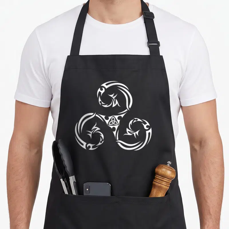 Tablier de cuisine noir avec un grand triskèle blanc et un triskélion au centre imprimé sur le dos.